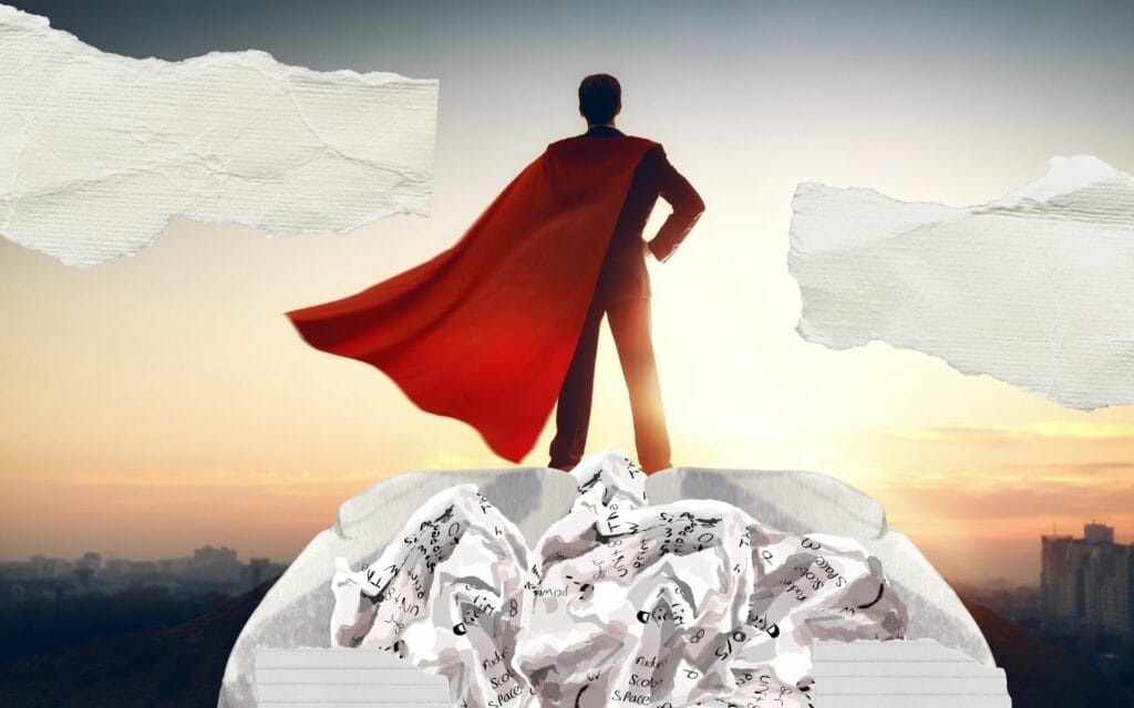 Person in cape stands over crumpled paper foreground.