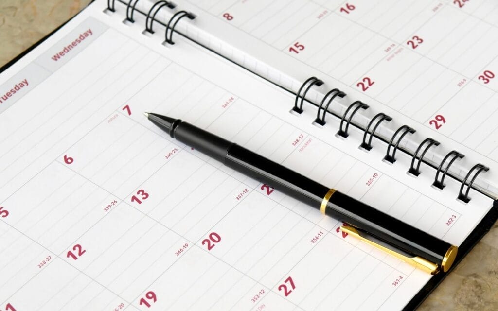 Black pen on open spiral-bound calendar.