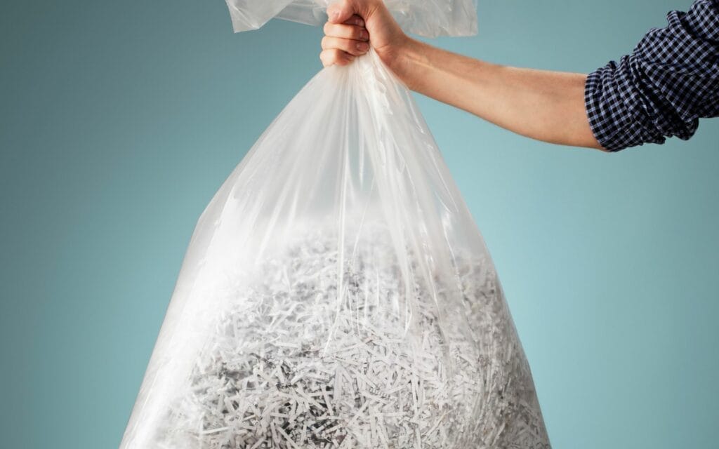 Hand holding shredded paper bag, recycling concept.