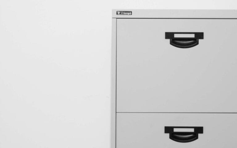 Gray metal filing cabinet with black handles.