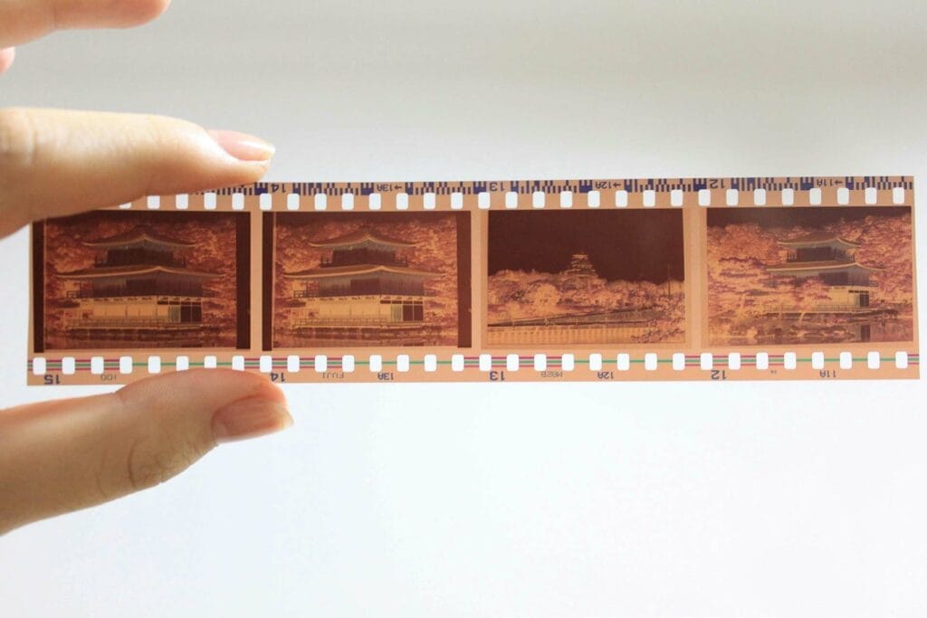 Hand holding film strip with building negatives.