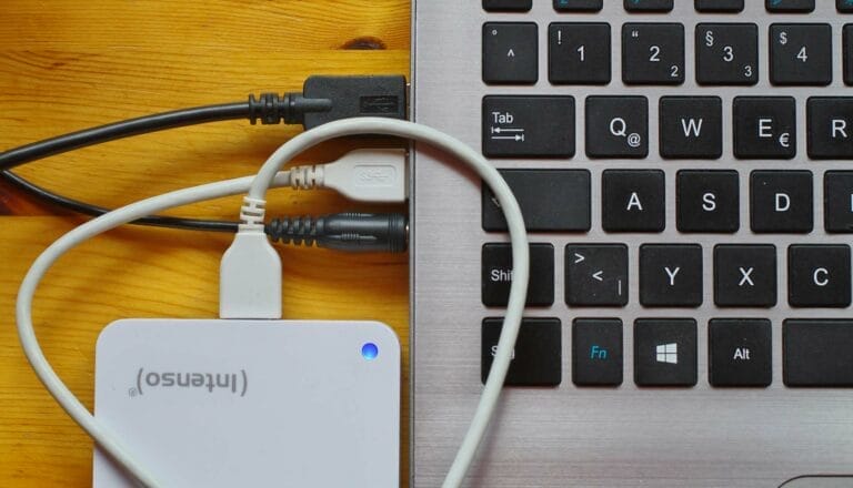Laptop with external drive connected by cables.