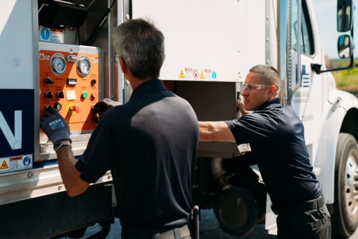 Men operating mobile shredding truck controls.