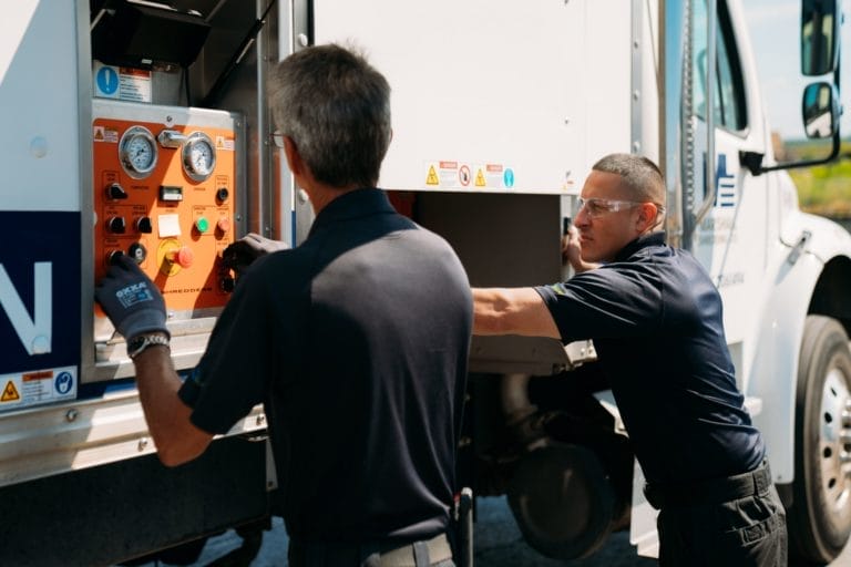 Men operating mobile shredding truck controls.