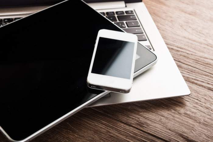 Laptop, smartphone, and tablet on wooden desk