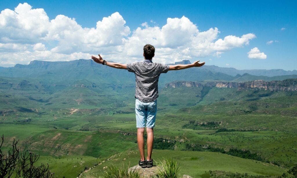 Person standing on mountain enjoying landscape view.
