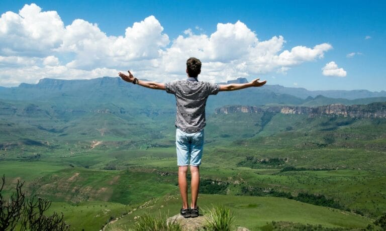 Person standing on mountain enjoying landscape view.