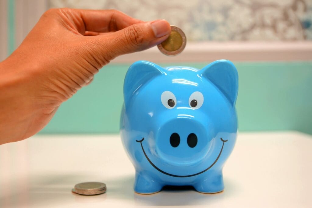 Hand placing coin in blue piggy bank