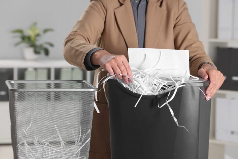 Person shredding documents into a waste bin.