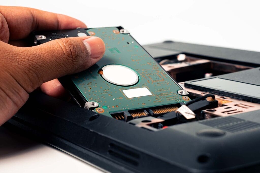 Hand installing a laptop hard drive.