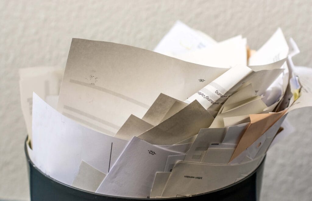 Overflowing trash bin with paper documents