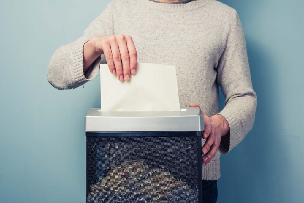 Person shredding paper with document shredder
