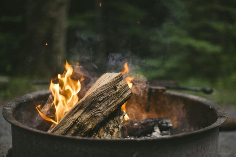 A cozy campfire burning with bright flames in a metal pit, perfect for a night outdoors.